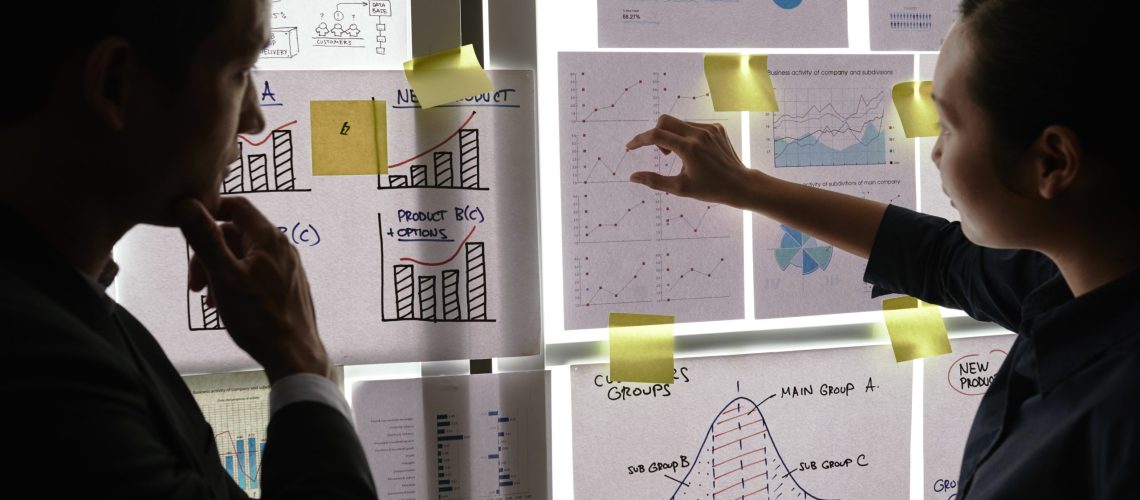 Financial managers analyzing financial reports and charts hanging on the wall