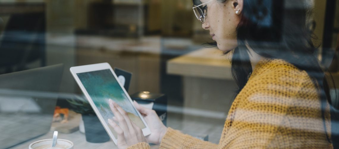 woman-with-coffee-tapping-tablet-screen